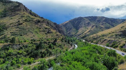 Poster - Aerial view of a lush valley with a winding river and road.