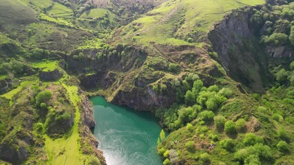 Wall Mural - Drone view over a green Lake in La Arboleda surrounded by lush green hills on a sunny day