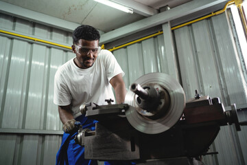 Canvas Print - A man is working on a machine in a workshop. He is wearing a white shirt and blue pants