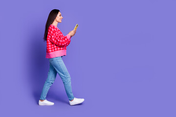 Canvas Print - Full length photo of cheerful pretty lady dressed pink cardigan chatting device walking empty space isolated violet color background