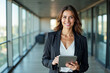 © Pixel Focus AI - Portrait of young Hispanic professional business woman standing in office. Happy female company executive, smiling businesswoman entrepreneur corporate leader manager looking at camera using tablet