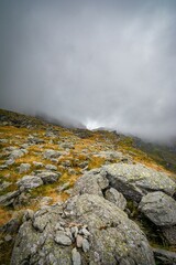 Poster - Rocky mountain landscape with overcast sky and mist, showcasing rugged terrain