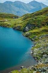 Wall Mural - Scenic view of a mountain lake surrounded by lush green hills and rocky terrain