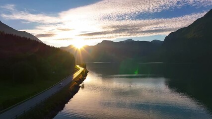 Sticker - Aerial footage of a white vehicle driving on a road a long a tranquil lake at sunset