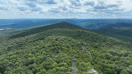 Poster - Aerial view of lush green mountain range under partly cloudy sky.