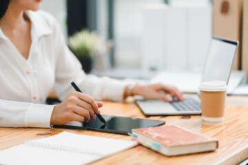 A person using tablet and laptop in modern workspace, showcasing productivity and creativity