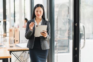 Wall Mural - Professional woman using tablet in modern office setting, smiling confidently