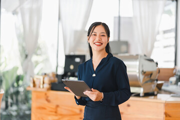 A confident woman smiles while holding tablet in cafe setting