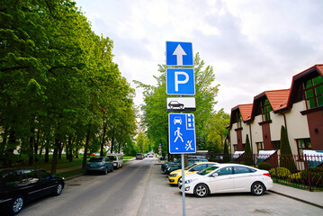 Wall Mural - Parking lot sign on pole in residential area, cars parked under green trees. Residential area traffic sign with specific regulations. Parking problems not enough free space. Crowded public parking lot