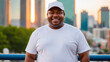 © QuoDesign - Plus size black man wearing white t-shirt and white baseball cap standing on cityscape background