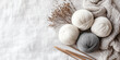 © Oleksandr - Three balls of yarn in neutral shades lie next to knitting needles and dried flowers on a bright surface, creating a calm, minimalist atmosphere.