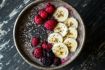 Wall Mural - A bowl of smoothie topped with bananas, berries, and chia seeds for a healthy meal.