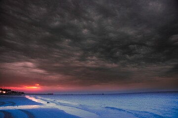 Wall Mural - Coastal Strip Under Cloudy Sky: A Sunset Bathing the Scene in Warm, Beautiful Hues