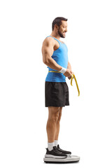 Sticker - Fit man in sportswear measuring waist and standing on a weight scale