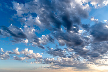 Beautiful white puffy clouds against blue sky during dramatic sunset