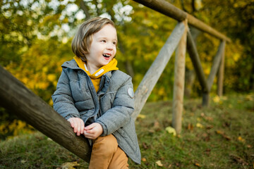 Wall Mural - Cute little boy playing outdoors on sunny autumn day. Child exploring nature. Fall activities for kids.