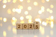 © Pcess609 - New Year Goals 2025. Flipping numbers 2024 to 2025 on a wooden block cube on a light bokeh background for preparation for the New Year change holiday. Happy New Year 2025.new Year's Eve Celebration.