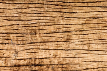 Closeup of rough, weathered, and cracked wood texture with brown and black tones.