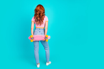 Wall Mural - Full body photo of attractive young woman back view hold pennyboard dressed stylish pink clothes isolated on cyan color background