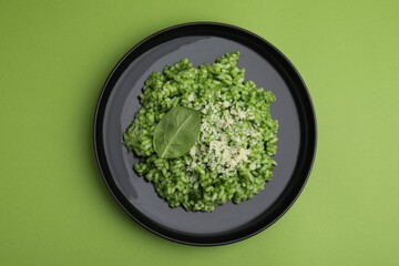 Delicious spinach risotto with parmesan cheese on light green background, top view