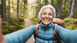© LIPO@SEXTAO22 - Senior woman taking a selfie while hiking in a forest, smiling and enjoying nature