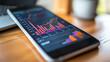 © Danielle - A close-up of a smartphone with a financial graph displayed on the screen