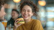 © Thanaphon - Smiling woman enjoying a delicious burger in a cozy restaurant, capturing a joyful moment of dining and socializing with friends.