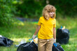 © Volodymyr - Environment plastic pollution. Volunteer kid collecting trash in the forest and holding a garbage bag. Environmental protection. Environmental Activist. Environmental conservation and waste pollution.