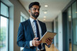 © Pixel Focus AI - Confident Indian business man leader looking aside walking in office. Busy professional businessman going in hallway holding digital tablet thinking of work plan using tab computer. Authentic photo