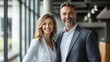 © Elmira - Two cheerful professionals stand side by side in a contemporary office space, smiling warmly and highlighting a positive work atmosphere