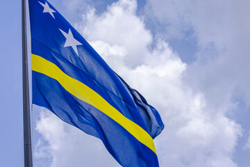 Close-up view of Curacao flag gently waving in wind with cloudy sky.