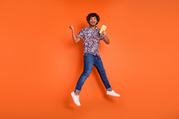 Canvas Print - Full size photo of nice young man jump winning hold device wear trendy colorful outfit isolated on orange color background