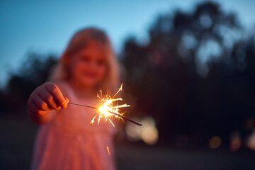 Girl, hand and night with sparkler for new year celebration, party or memory in nature. Young child, female person or kid with firework or sparks for December holiday, festive time or outdoor magic