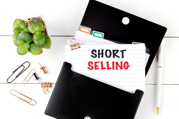 Poster - Short selling concept with index cards, pen, office supplies, and plant on a white desk