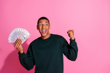 Canvas Print - Photo of lucky funny guy wear sweatshirt rising fist winning cash fan emtpy space isolated pink color background