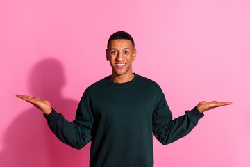 Poster - Photo of cheerful positive guy dressed pullover comparing two arms emtpy space isolated pink color background