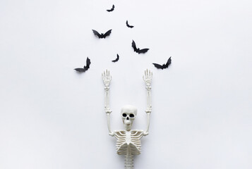 Skeleton and paper bats for Halloween party on white background