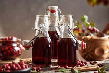 Wall Mural - Three bottles of medicinal wine prepared from fresh hawthorn berries ans spices