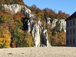 stone rocks are overgrown with colorful autumn trees. under part of the house can be seen through th