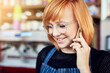 © Penn/peopleimages.com - Phone call, waitress and woman with smile in shop, glasses and communication for schedule of shift. Cafe, barista and person with mobile, happy and talking with contact, apron and order to supplier