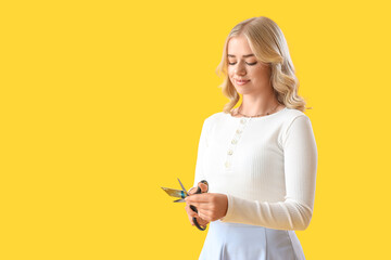 Poster - Young woman cutting credit card on yellow background