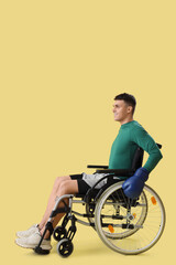 Wall Mural - Sporty young man in wheelchair with boxing gloves on yellow background