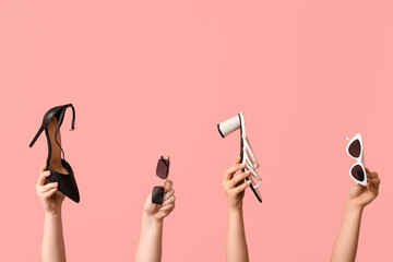 Wall Mural - Female hands with different sunglasses and heeled shoes on pink background