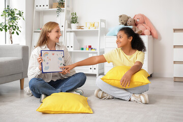 Sticker - Female psychologist showing drawings to African-American girl in office