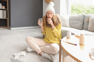 Wall Mural - Ill young woman with glass of water sitting at home