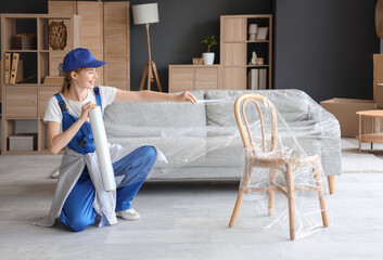 Wall Mural - Female worker wrapping chair with stretch film in room