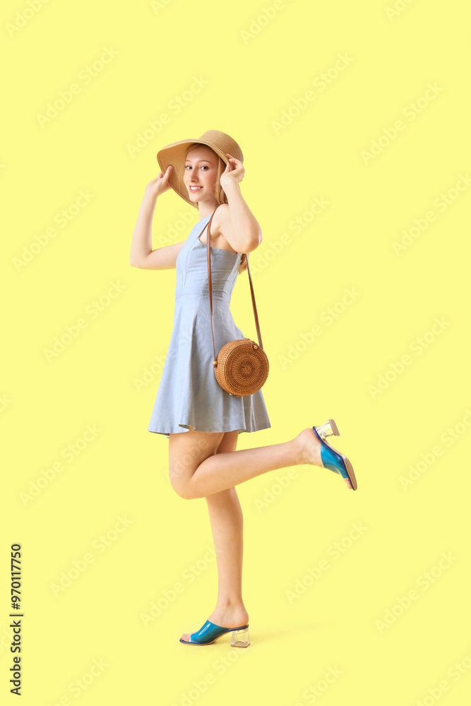 Young pretty woman in hat on yellow background