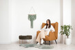 © Pixel-Shot - Young woman sitting in armchair in living room
