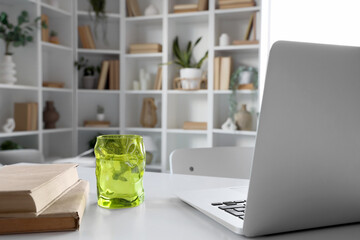 Wall Mural - Glass of water, books and laptop on table in home library