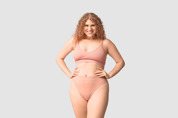 Wall Mural - Beautiful young happy body positive woman in trendy underwear on grey background